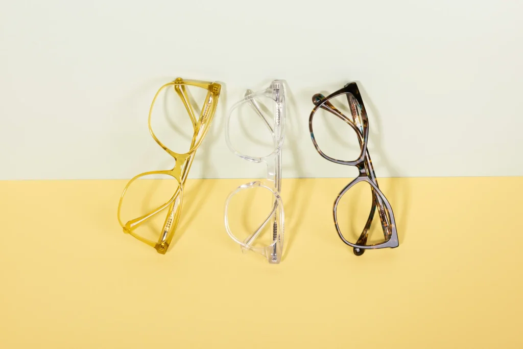 Photographie de trois lunettes de vue jaune, grise et noire