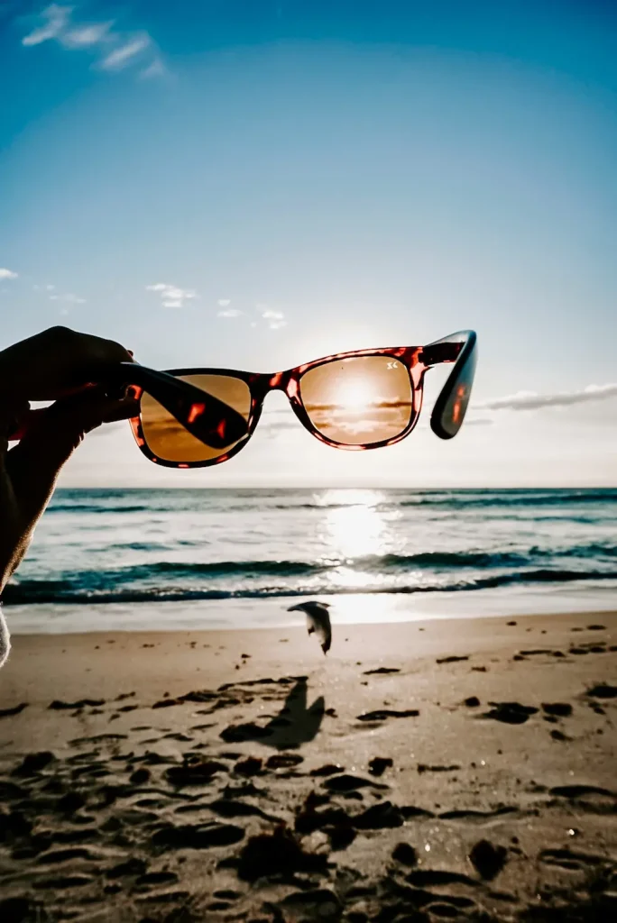 Personne tenant des lunettes de soleil à la main à la plage